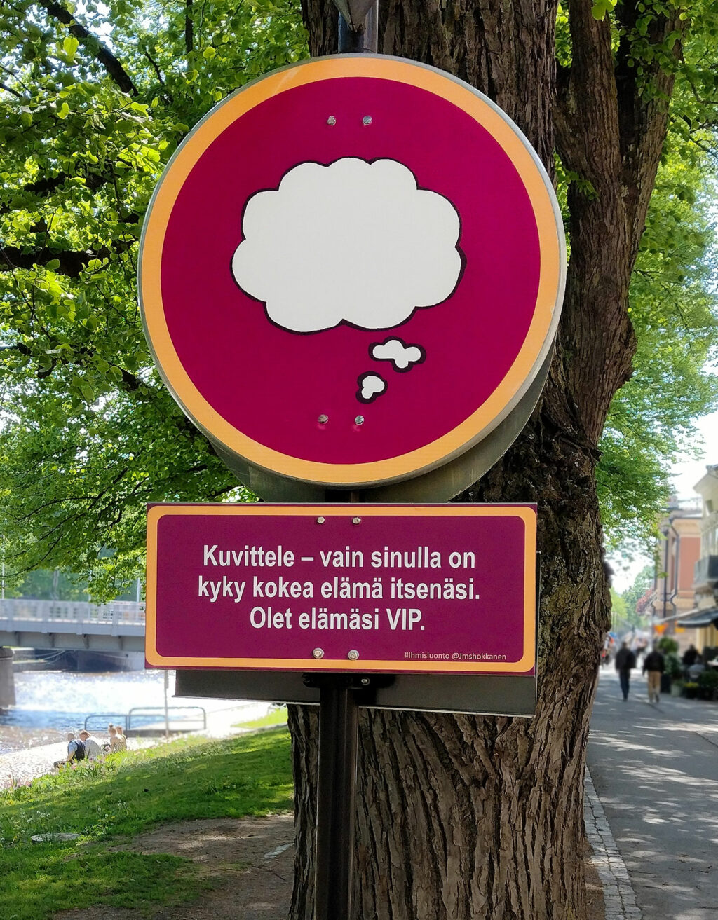 Viininpunaiset liikennemerkkiä muistuttavat kyltit puun rungossa.